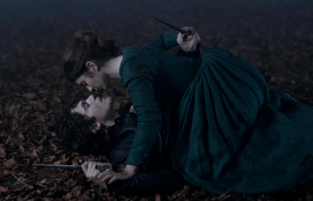 A promotional image of Jane straddling Guildford, each of them holding a dagger. Their lips are nearly touching.