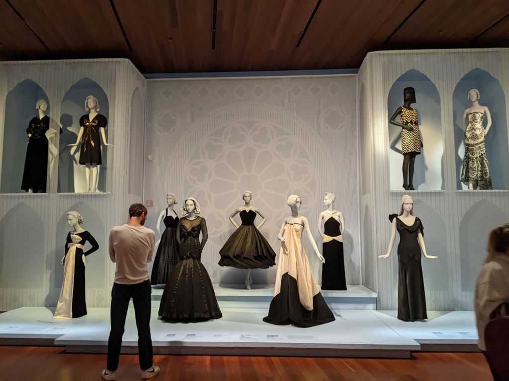 A view of one section of an exhibition, with a wide array of mannequins in black and white dresses.